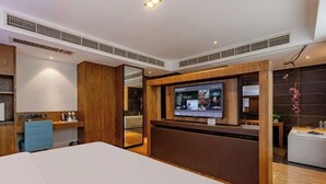 Une chambre d’hôtel avec un lit, une télévision, un bureau et un miroir.