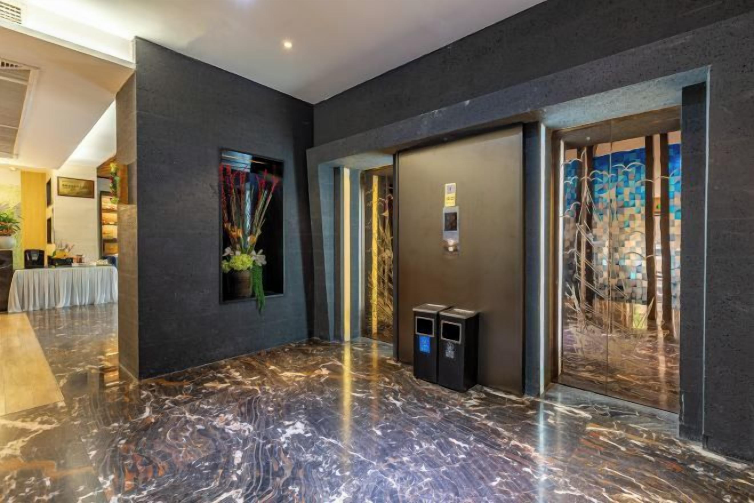 A lobby with a marble floor, a reception desk, and a wall-mounted elevator control panel.
