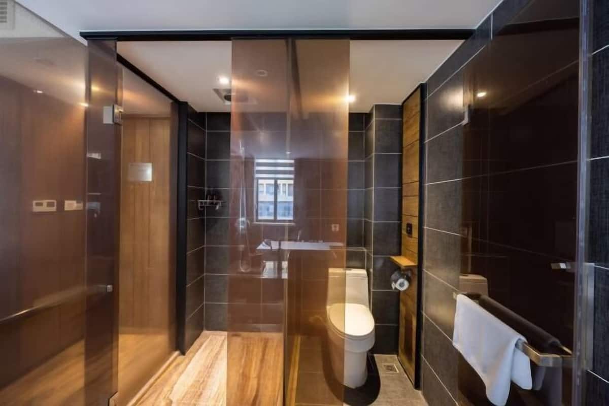 Egy modern fürőszoba üveg válaszfallal ellátott zuhanyzóval, WC-vel és mosdókagylóval.