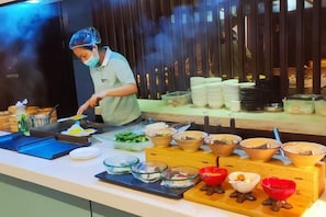 A buffet setup with various food items and a person serving. - Bonilyi Hotel (Ningbo Beilun Yintai City ) (Ningbo)