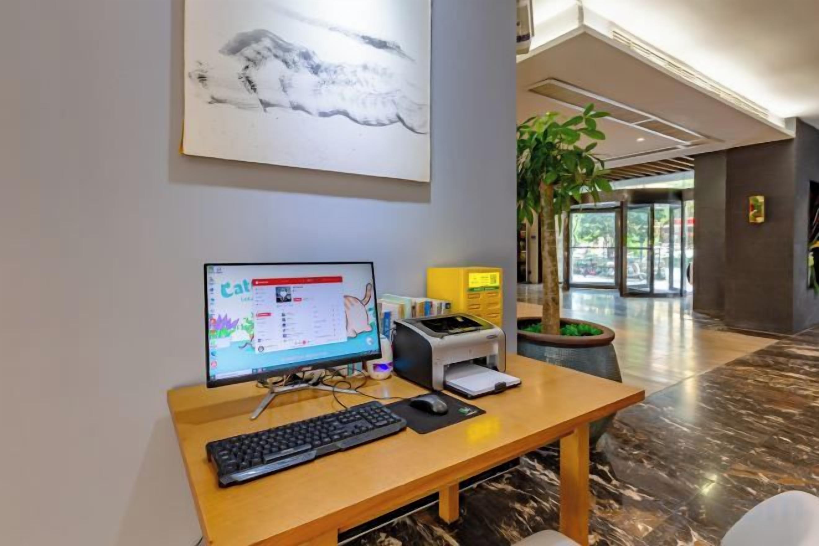 A reception desk with a computer, keyboard, and a plant.