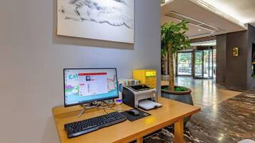 A reception desk with a computer, keyboard, and a plant.