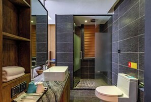 A modern bathroom with a marble countertop, a sink, a toilet, and a shower area.