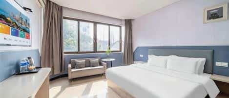 A hotel room with a bed, a sofa, a desk, and a window.