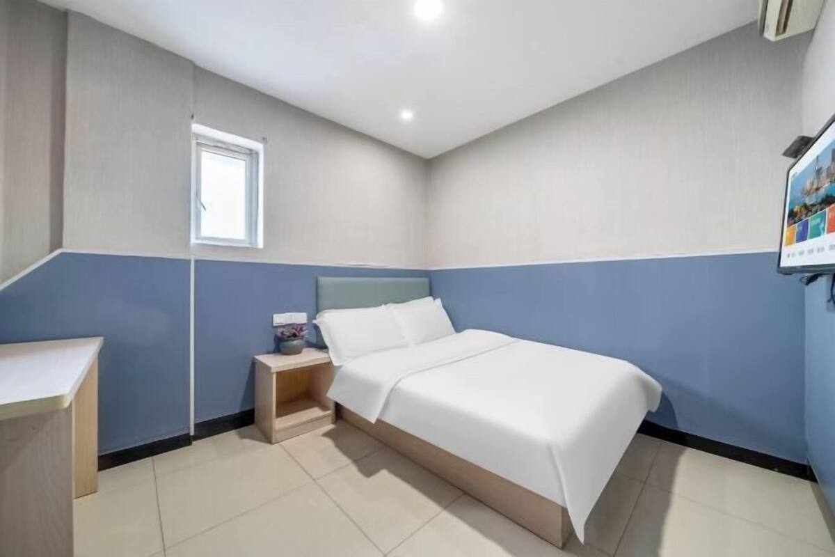 A bedroom with a bed, bedside table, and a small window.
