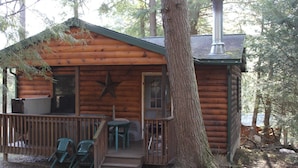 A log cabin with a deck, two chairs, and a star decoration. - Hominy Ridge Cabins and Gift Shop (Clarington)