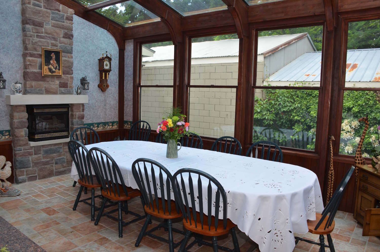 A dining area with a stone fireplace, a table with a white tablecloth, and chairs.