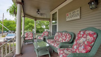 Une véranda meublée de meubles en osier et une enseigne indiquant « The Inn of Saugatuck ».