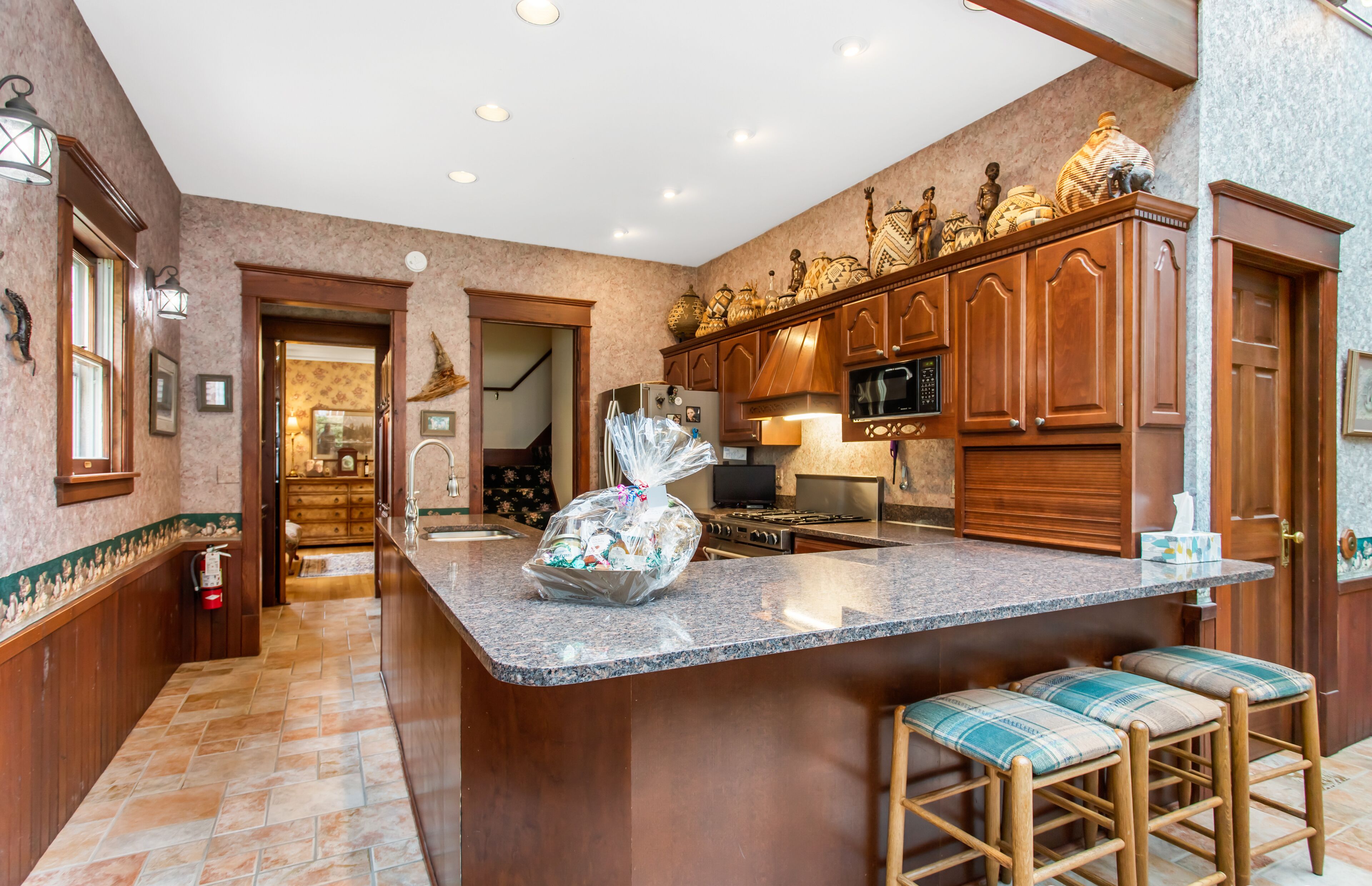 A spacious kitchen with a large island, wooden cabinets, and a microwave.