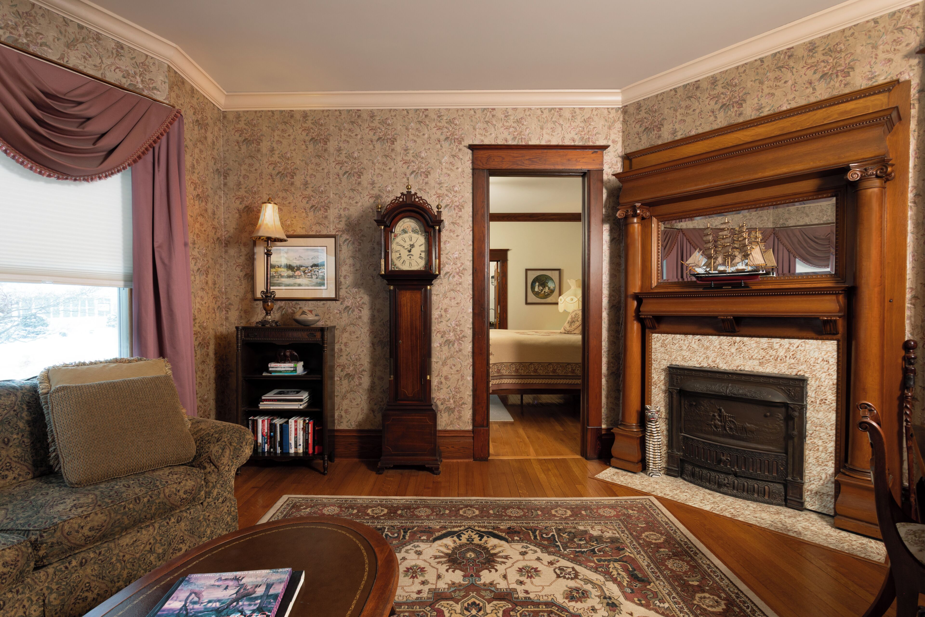 A living room with a sofa, a coffee table, a fireplace, a clock, and a bookshelf.