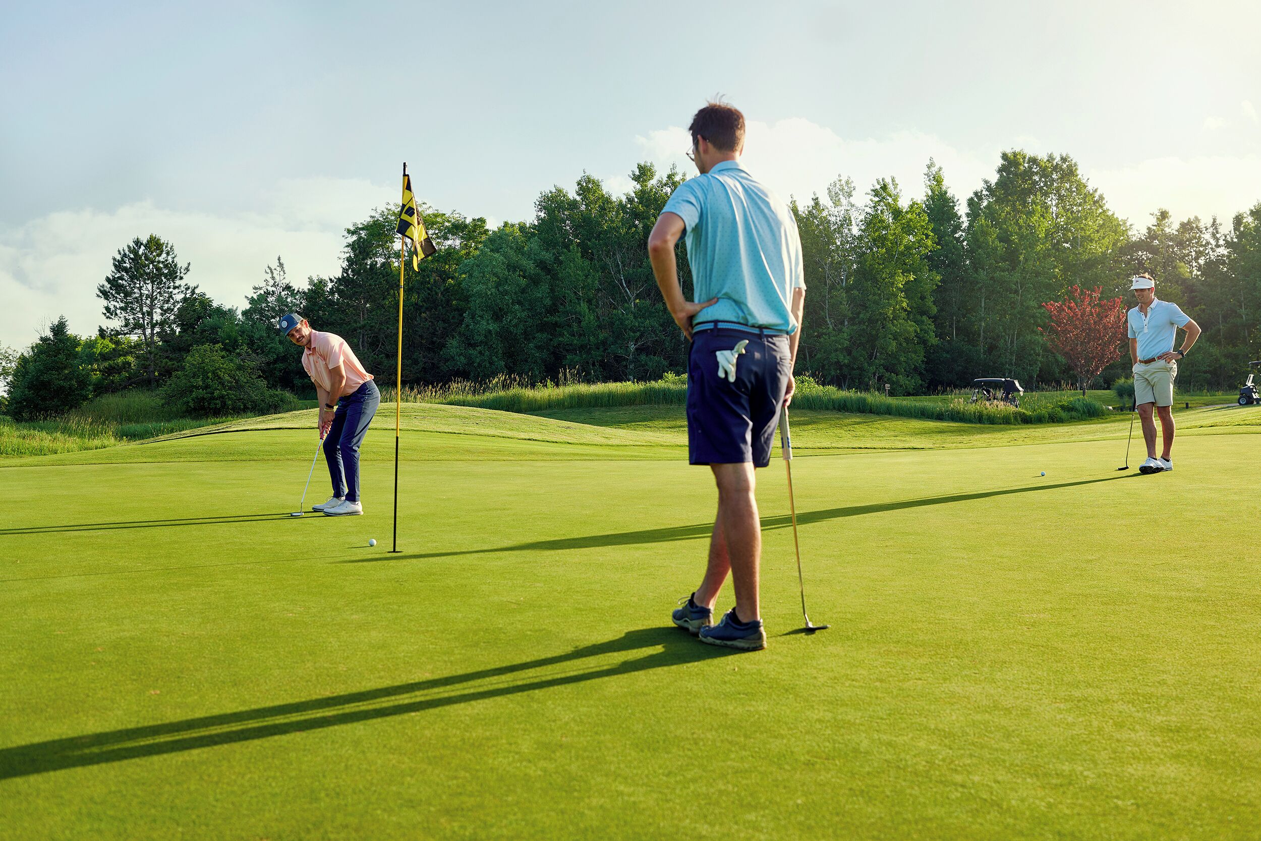 A golf course with players and a flagstick.