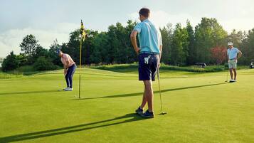 A golf course with players and a flagstick.