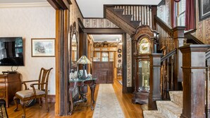 Una imponente escalera con detalles ornamentales de madera, un banco de madera y una mesa con una lámpara.