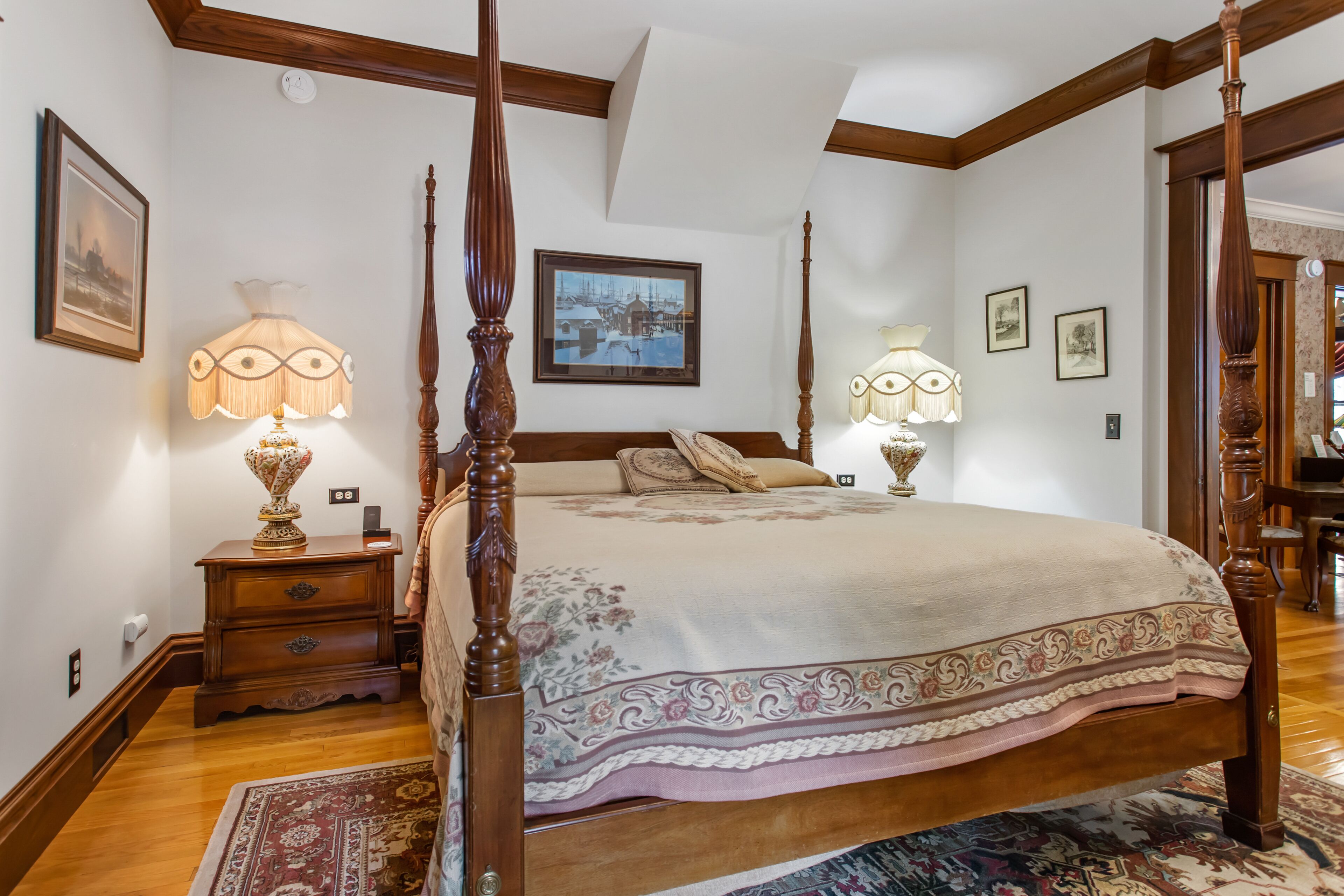 A bedroom with a four-poster bed, wooden nightstands, and a large window.