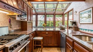 Una cocina con armarios de madera, estufa a gas, una isla grande con pileta y vistas por las ventanas.