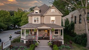 Una casa de dos pisos con un porche, banderas estadounidenses y un letrero que dice The Inn of Saugatuck.