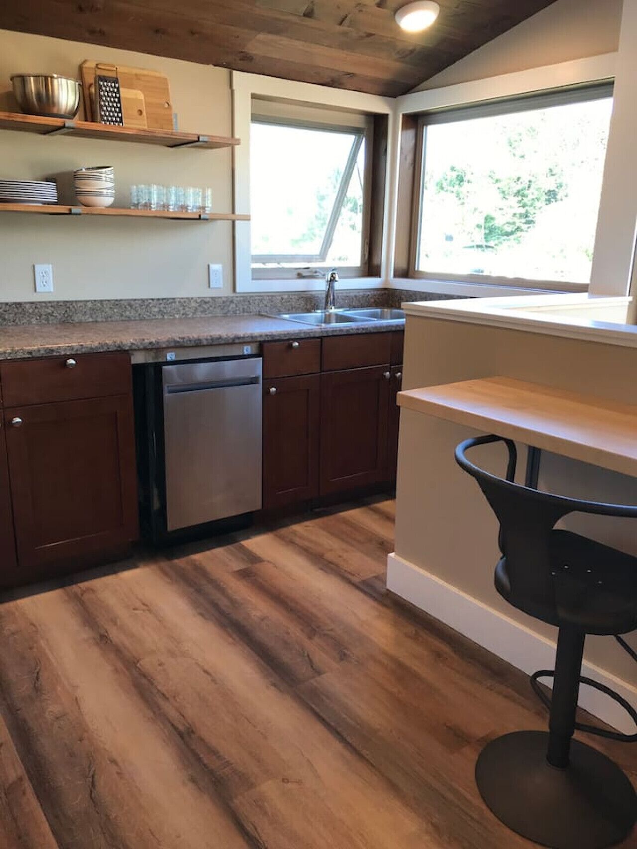 A modern kitchen with wooden cabinets, a dishwasher, and a window providing natural light.