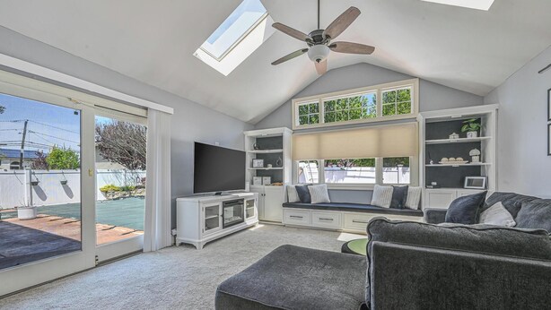 A spacious living room with a ceiling fan, a large TV, and a built-in bench with storage. - Prime Ryder Cup Location - Spacious 4 Bedroom Retreat with Pool, Outdoor Kitchen (Seaford)