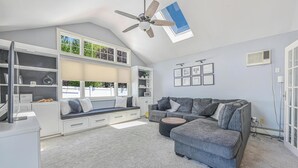 A spacious living room with a grey sofa, a built-in bench, and a ceiling fan. - Prime Ryder Cup Location - Spacious 4 Bedroom Retreat with Pool, Outdoor Kitchen (Seaford)