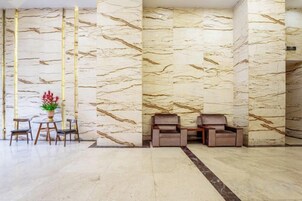 Un vestíbulo con paredes de mármol, una recepción y una zona de estar.