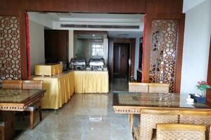 A dining area with tables and chairs, a buffet setup, and a decorative screen.