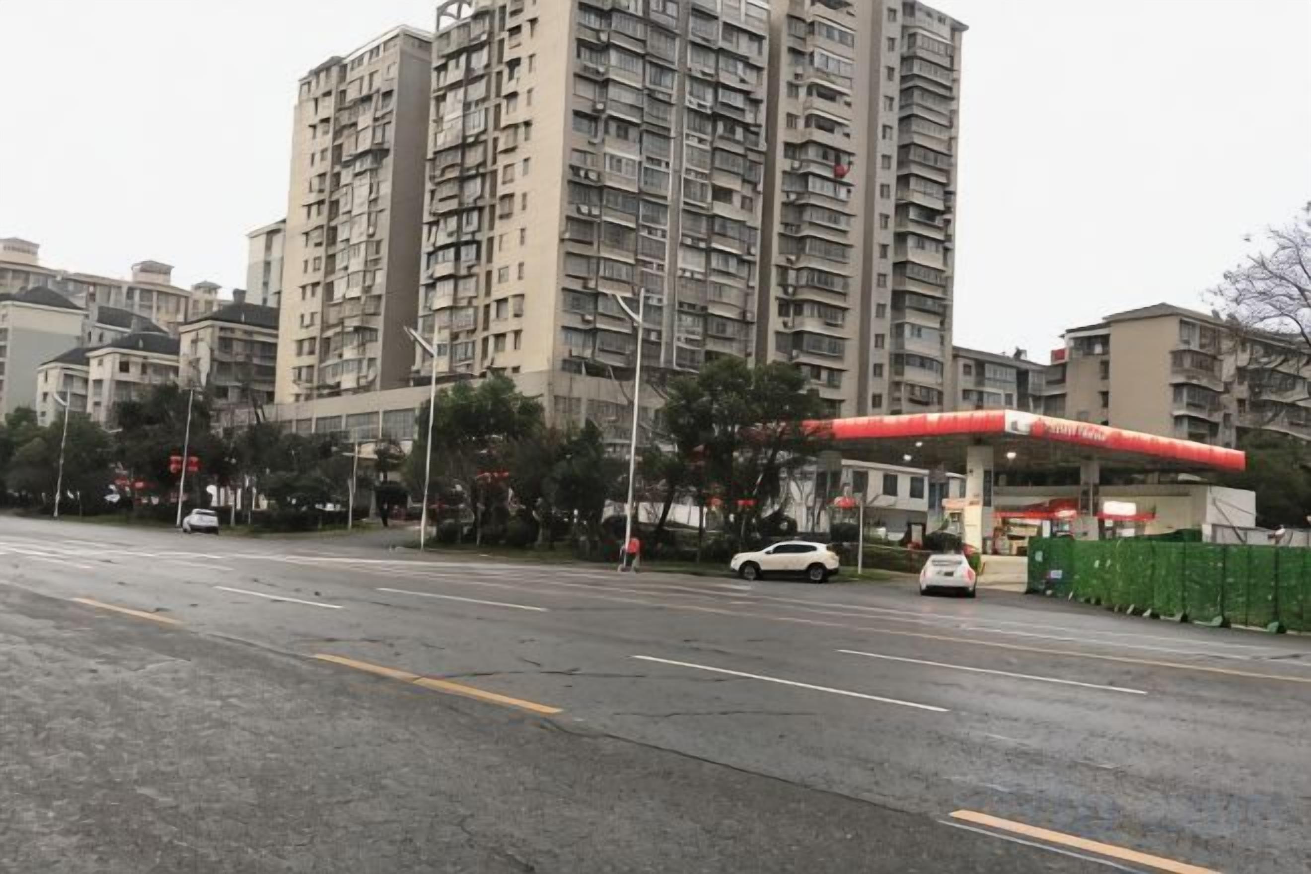 Un edifici residencial de diverses plantes amb una benzinera al primer pla.