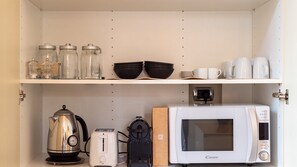 A kitchen with a kettle, toaster, microwave, and storage jars on the shelves. - [130 sqm - Lima M1] Elegant & Luxury Design Flat (Milano)