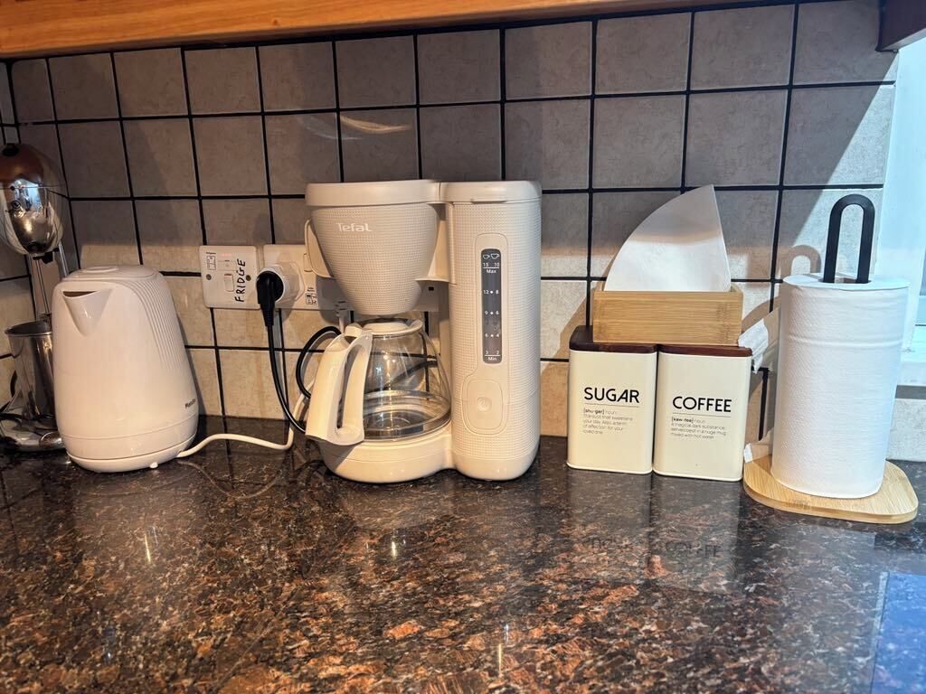 Eine Küchenarbeitsplatte mit Kaffeemaschine, Wasserkocher sowie Zucker- und Kaffeepackungen.