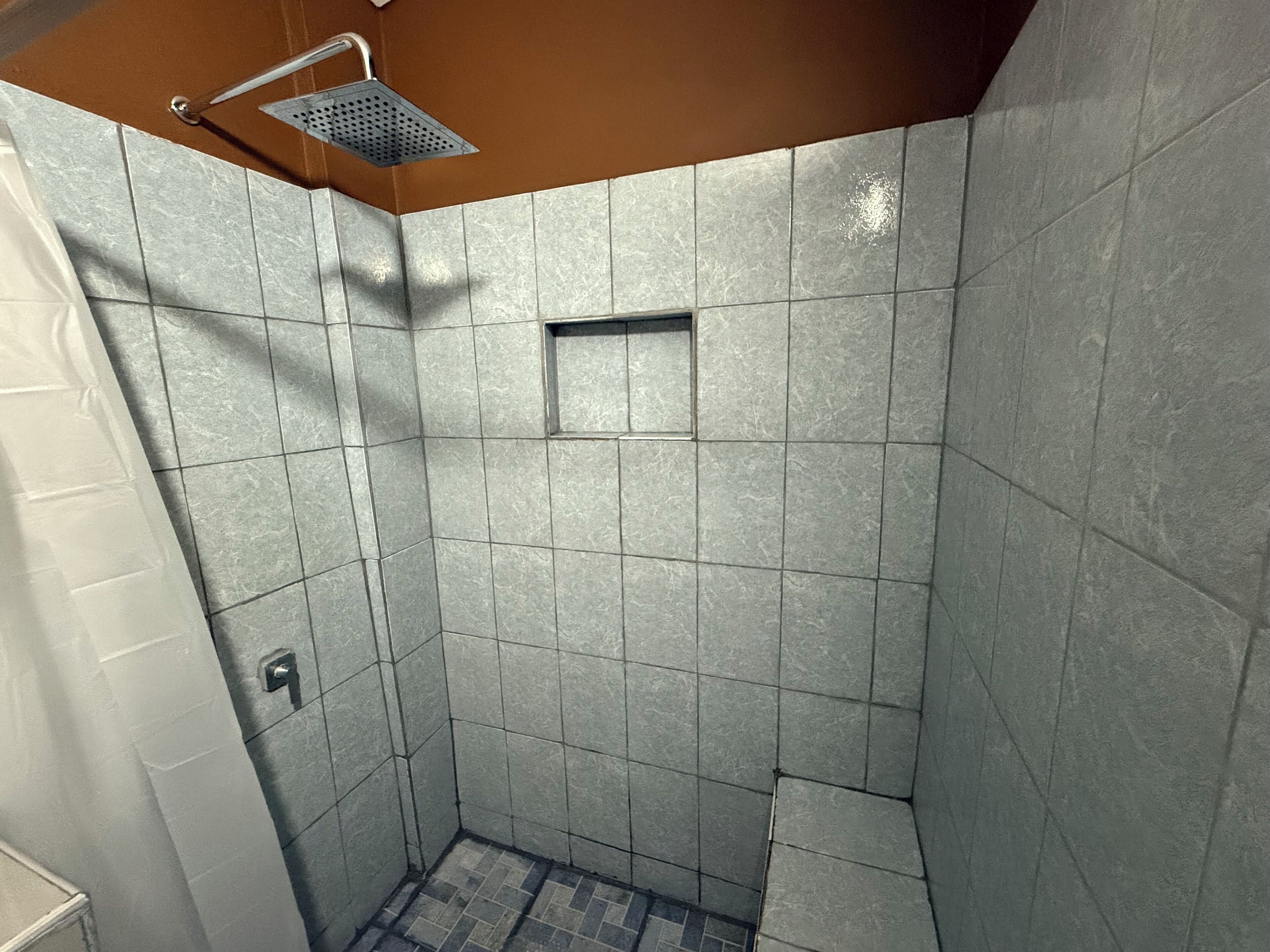 A small, tiled shower area with a showerhead and a small window.