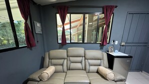 A room with a large, beige sectional sofa, a small table with a sign, and a window with curtains. - El Mangal B&B (Suchitoto)