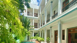 Un immeuble à plusieurs étages doté d’une piscine, entouré d’une végétation luxuriante et de plantes en pot.