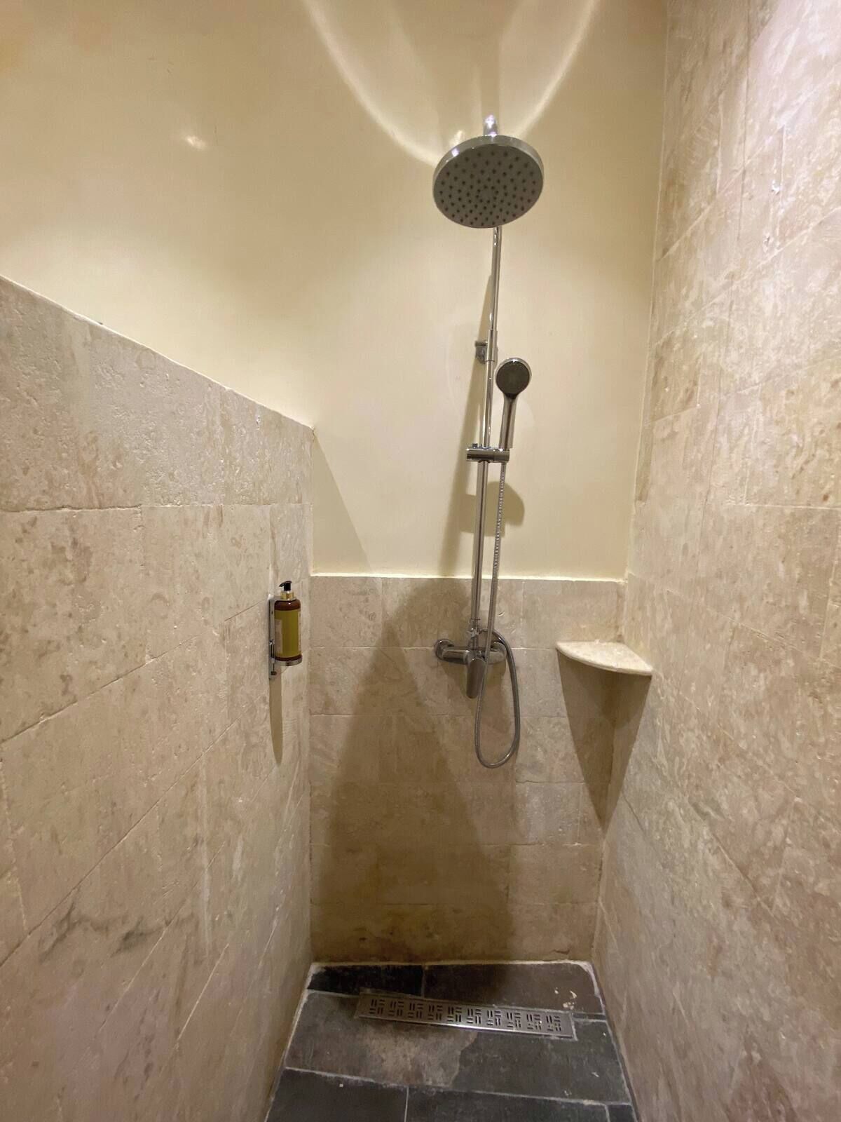 A small, tiled shower area with a handheld showerhead and a wall-mounted faucet.