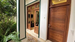 Un couloir avec un sol à motifs, des portes en bois et une plante en pot.