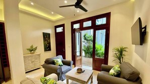 Un salon moderne doté d’un ventilateur de plafond, de deux canapés, d’une table basse et d’un meuble.