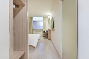 Ein Hotelzimmer mit Bett, Schreibtisch, Stuhl, Heizkörper und Fenster.