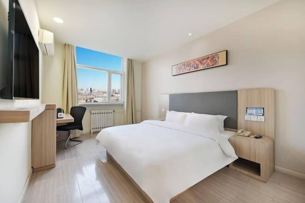 Habitación de hotel con cama, escritorio, silla y vista a la ciudad.