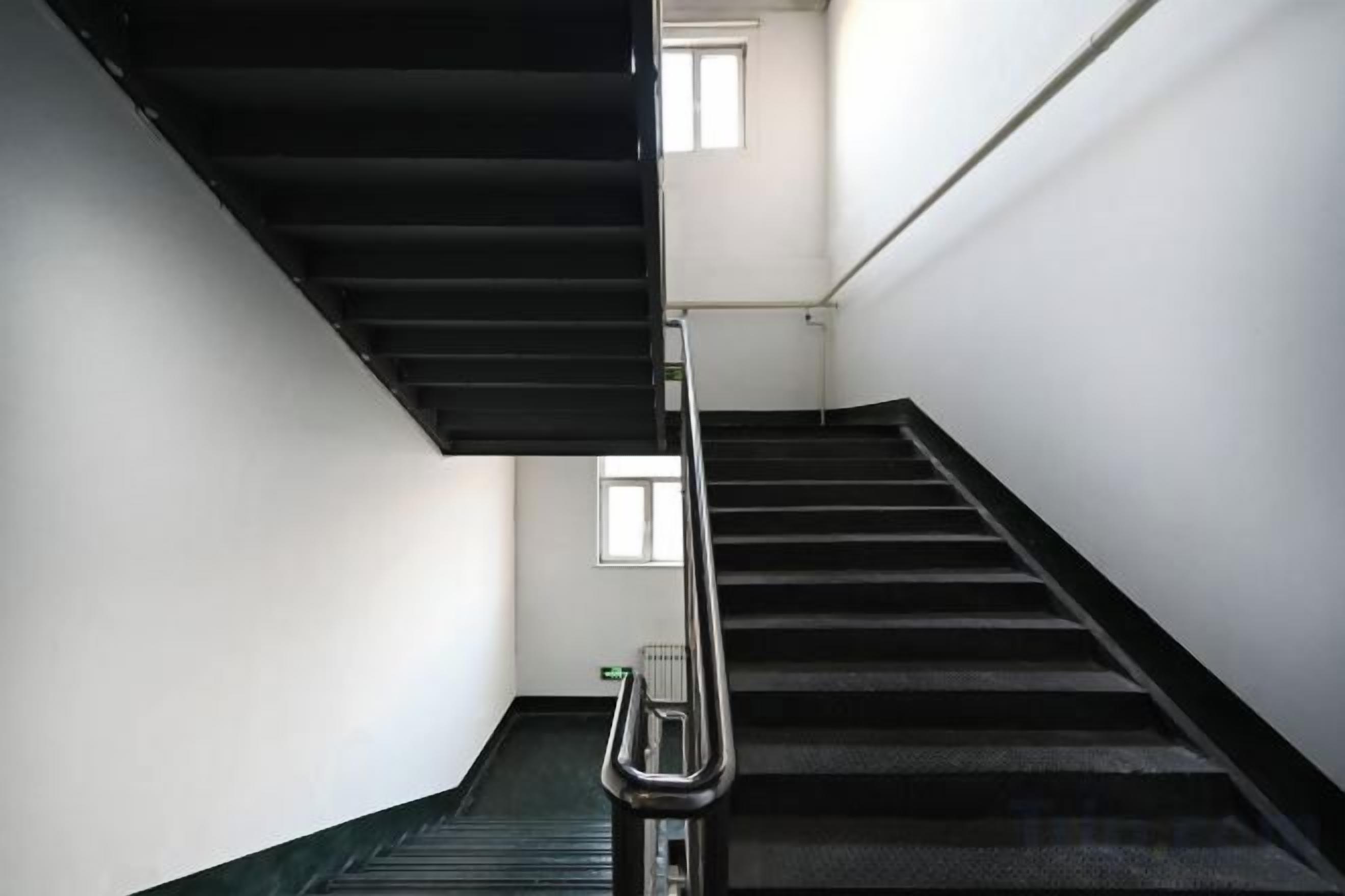 A staircase with a handrail, a landing area, and a window at the top.
