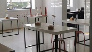Un espacio de oficina moderno con mesas blancas, taburetes rojos y decoración minimalista.