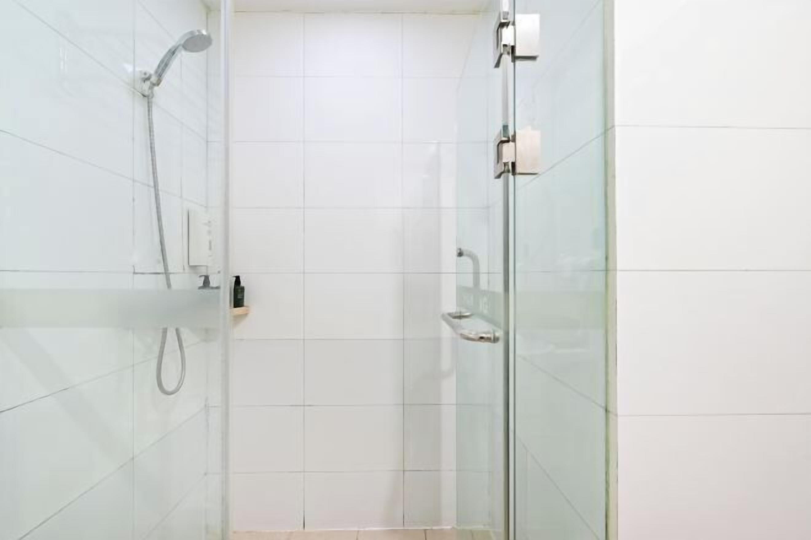 A glass-enclosed shower with a handheld showerhead and a wall-mounted faucet.