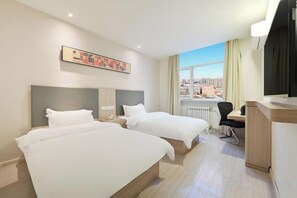 Une chambre d’hôtel avec deux lits, un bureau et une vue sur la ville.