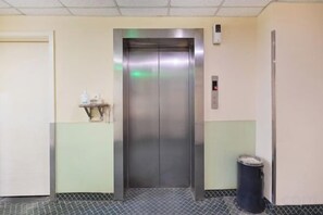 Ein Aufzug in einer Diele, rechts daneben ein Mülleimer.