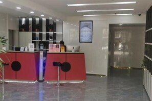 A reception area with a red desk, a mirror, and a framed picture on the wall. - Nanshu Thatched Cottage Hotel (Huihua College Branch of Shijiazhuang Railway Station) (Shijiazhuang)