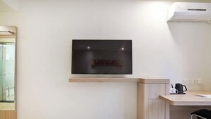 Una habitación moderna con televisión montada, un escritorio de madera y una silla.