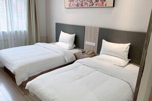 Ein Hotelzimmer mit zwei Betten, einem Nachttisch, einem Telefon und einem Fenster mit Vorhängen.