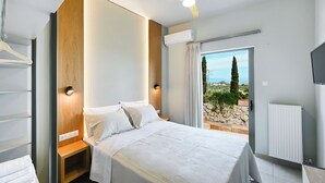 Ein modernes Schlafzimmer mit Bett, Nachttischen, Deckenventilator und Blick ins Freie.