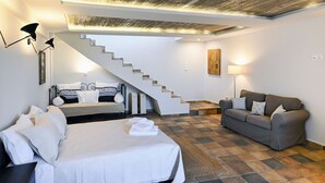 Ein modernes Schlafzimmer mit einem Bett, einem grauen Sofa, einer Treppe und einem an der Wand hängenden Kunstwerk.