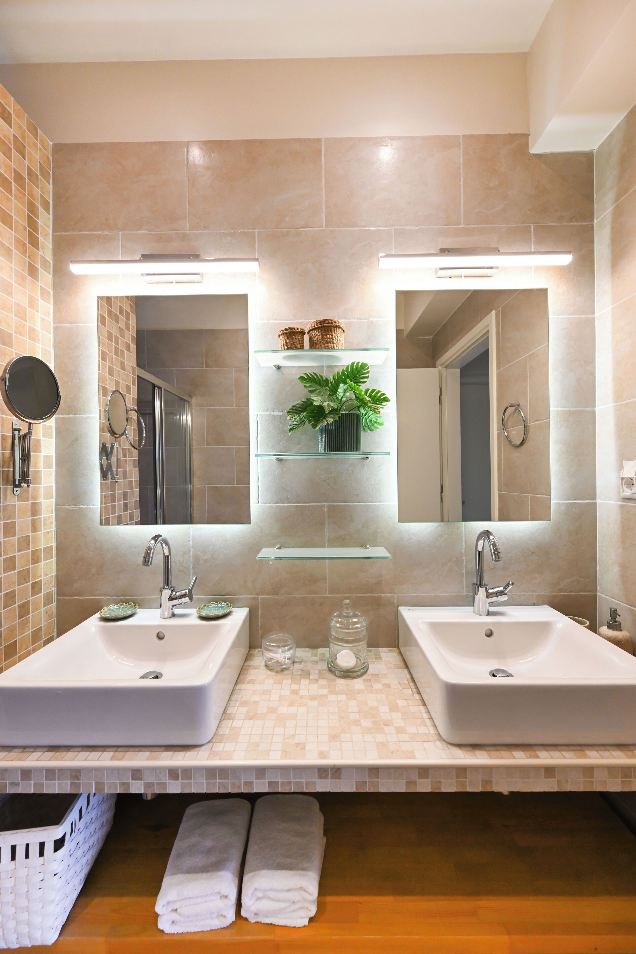 A bathroom with two sinks, a mirror, and shelves with toiletries.