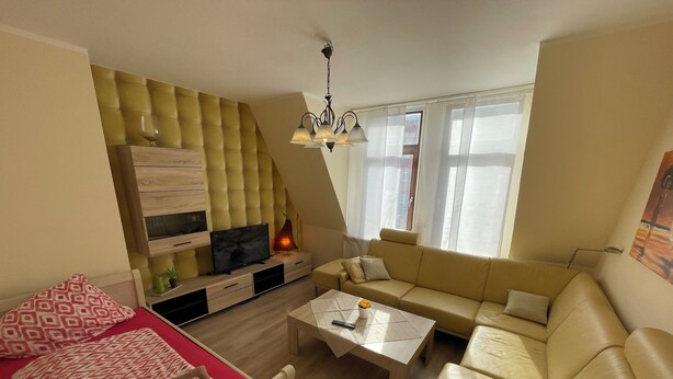 A modern living room with a sofa, a bed, a TV, and a coffee table. - Cozy vacation apartment - perfect for a short break all inclusive for 5 people (Bremerhaven)
