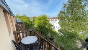 A balcony with a round table and two chairs, overlooking a garden and buildings. - Cozy vacation apartment - perfect for a short break all inclusive for 5 people (Bremerhaven)