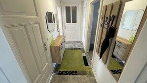 A hallway with a wooden bench, a green rug, and a door at the end. - Cozy vacation apartment - perfect for a short break all inclusive for 5 people (Bremerhaven)